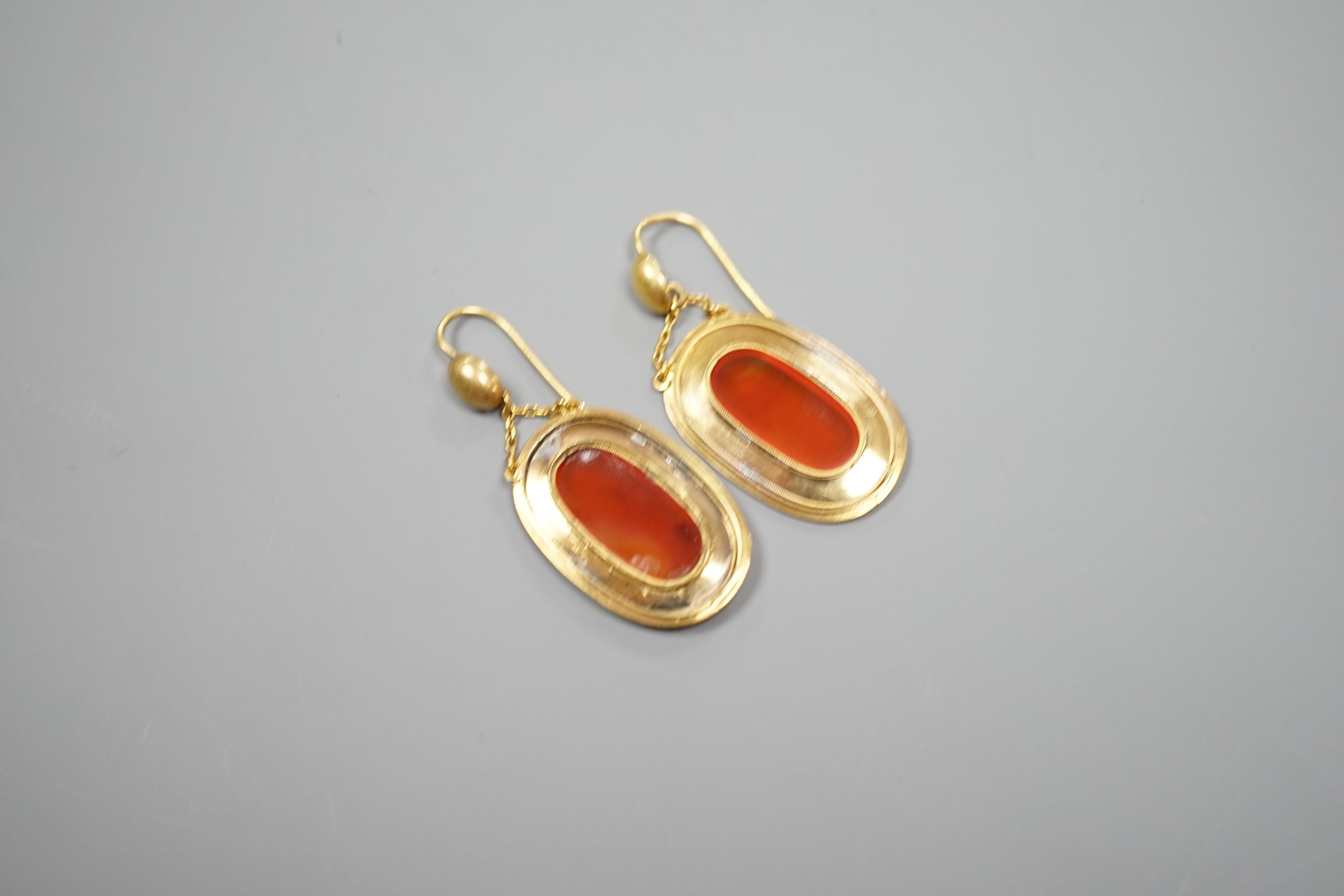 A pair of yellow metal and orange agate set oval drop earrings, overall 46mm, gross 6.8 grams.